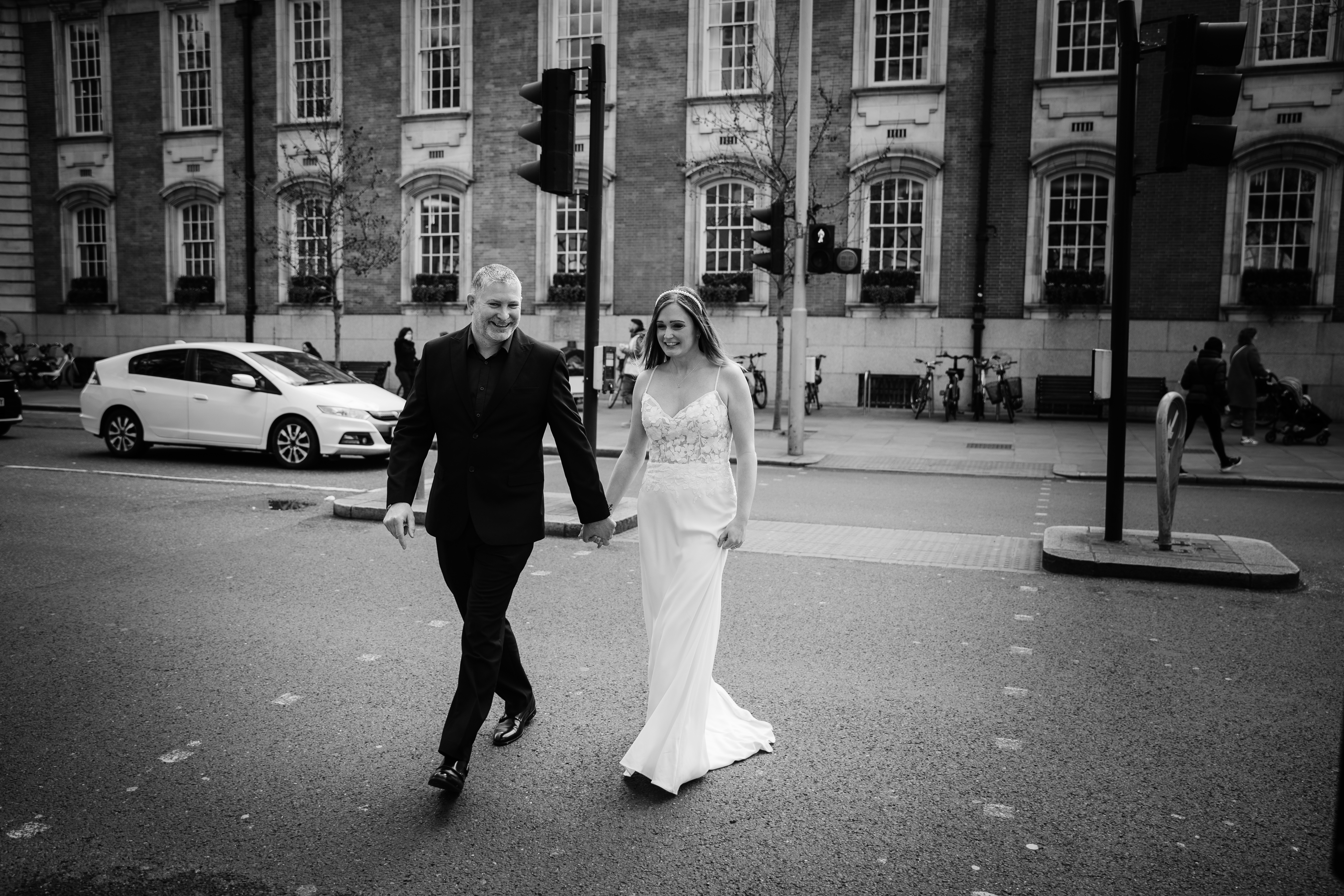 Relaxed couple portrait of Olivia and Nathan crossing the road outside Chelsea Town Hall after their ceremony