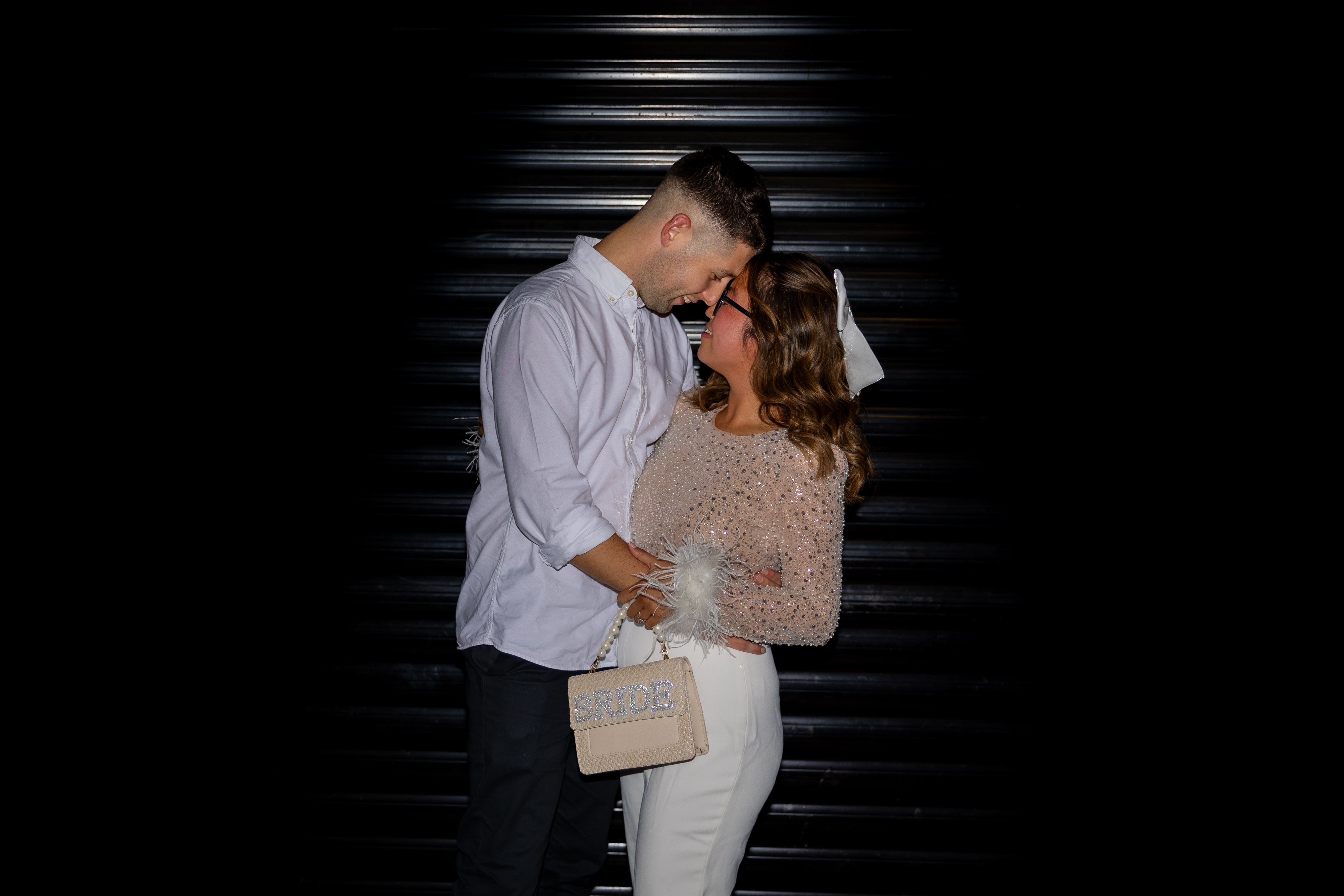Engaged couple Emily and James sharing a quiet moment outside their London Bridge venue at night, lit by streetlight.